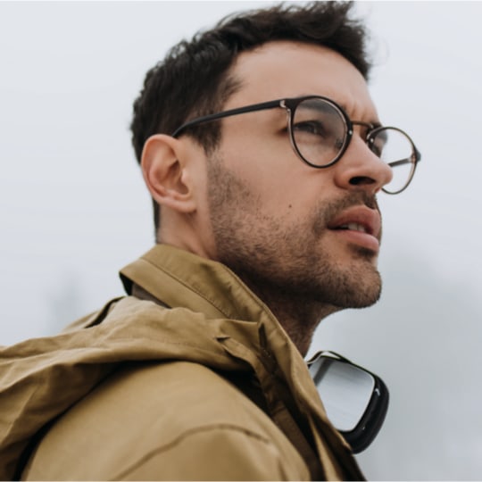 white male with round glasses against white background, looking off into the distance