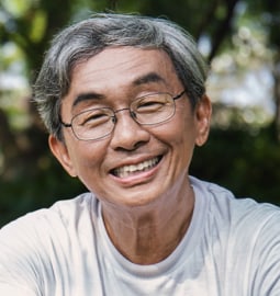 mature asian man portrait shot sitting outside and smiling