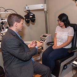 optometist showing patient a model of an eye