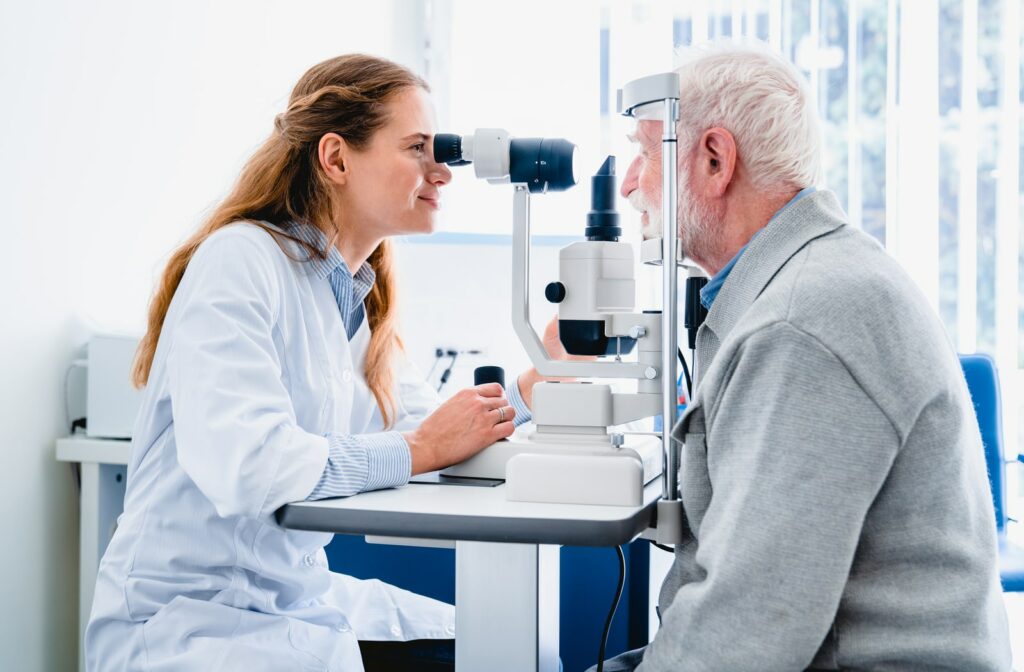 An older male patient receiving an eye exam from a female optometrist to check for eye diseases or issues