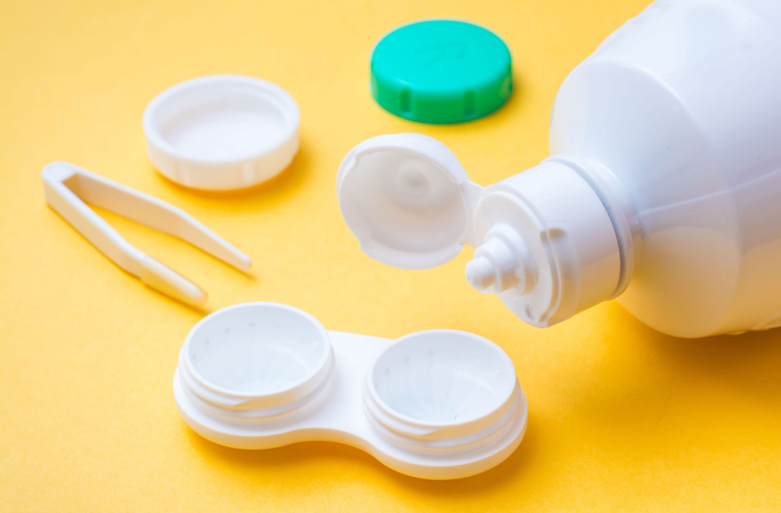 Contact lens cleaning fluid is poured into an open container for storing lenses.