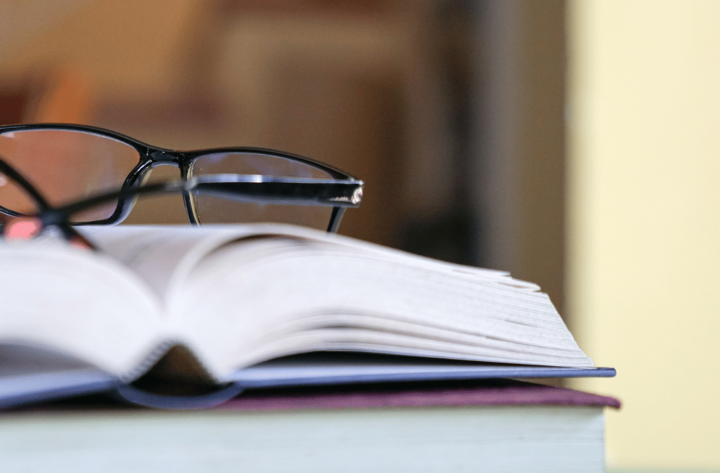 A pair of reading glasses sit on top of an open book