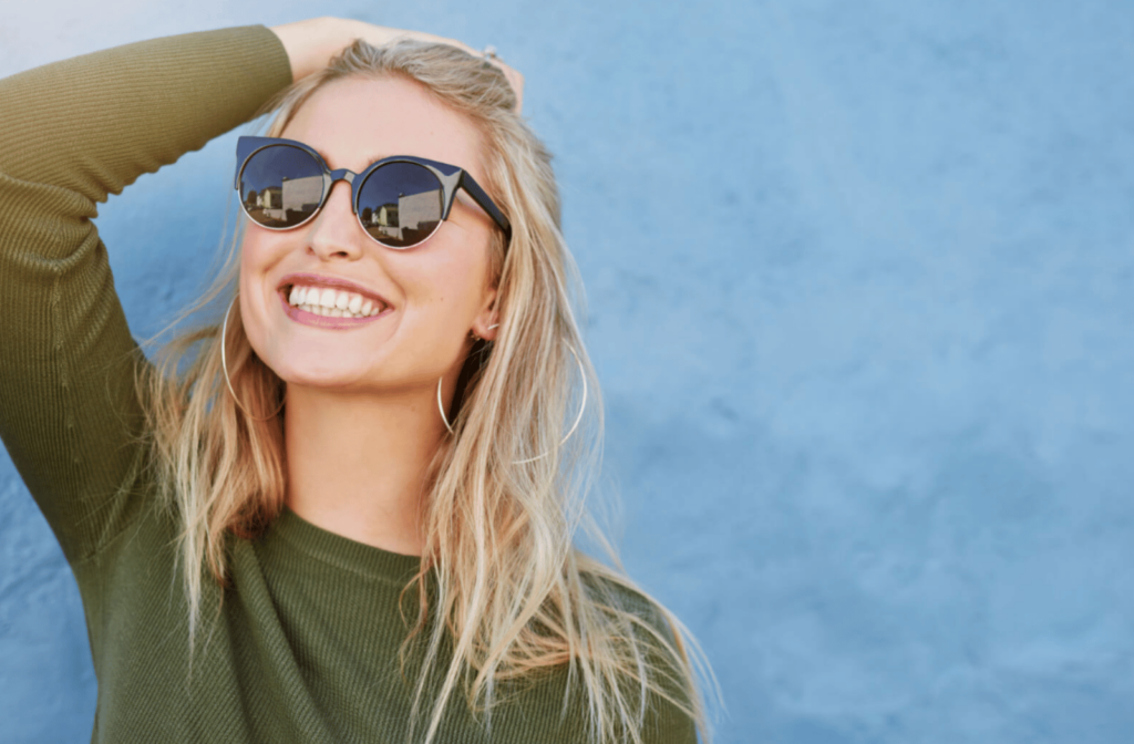 Young happy woman wearing sunglasses looking at the sky