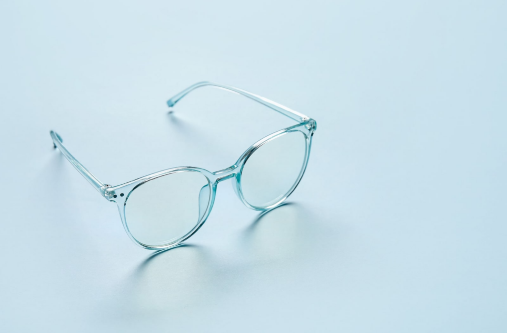 A pair of transparent blue glasses sitting on a blue backdrop