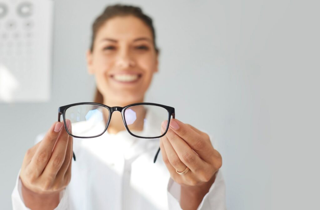 An optician holds out a pair of fitted glasses towards the camera