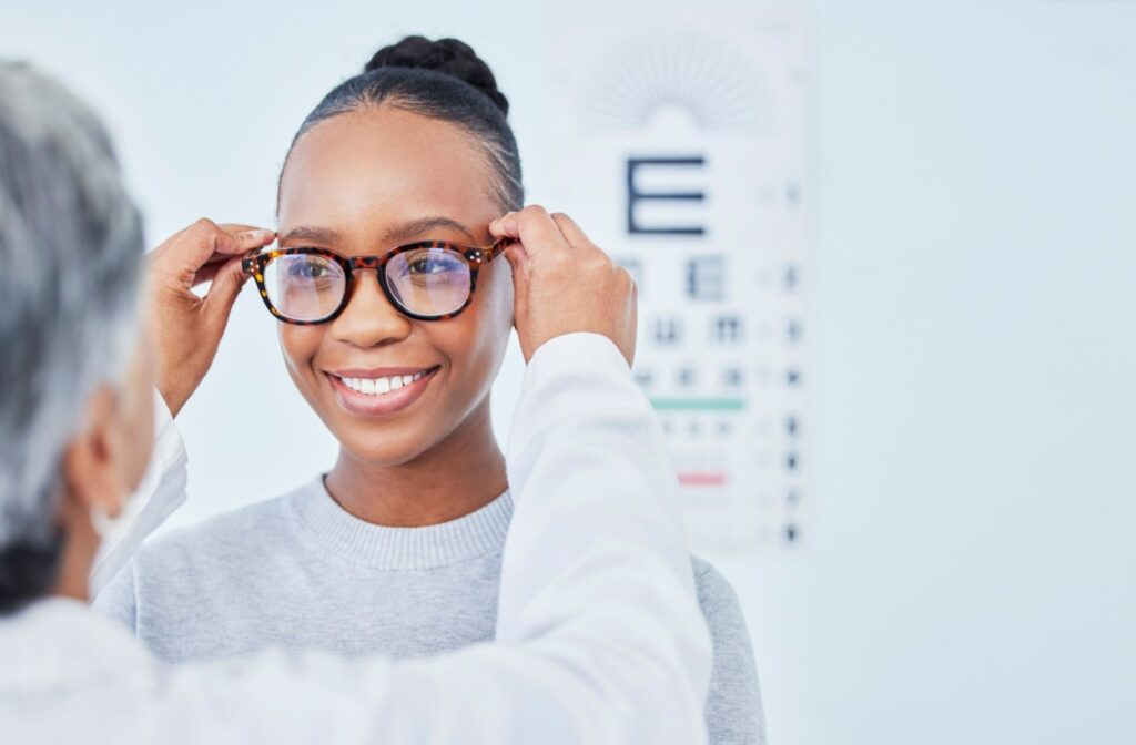 A young female patient with glasses is happy during her routine eye exam.