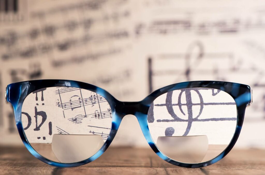 A close-up showing the dual-vision lens design of bifocal glasses against sheet music.