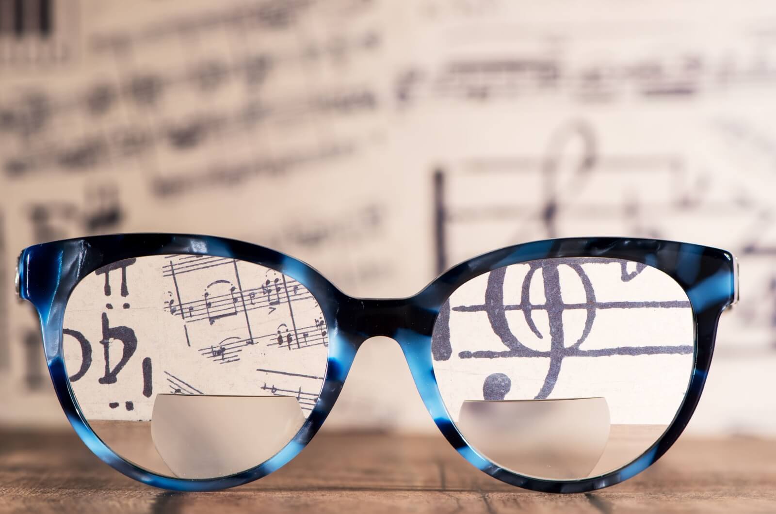 A close-up showing the dual-vision lens design of bifocal glasses against sheet music.