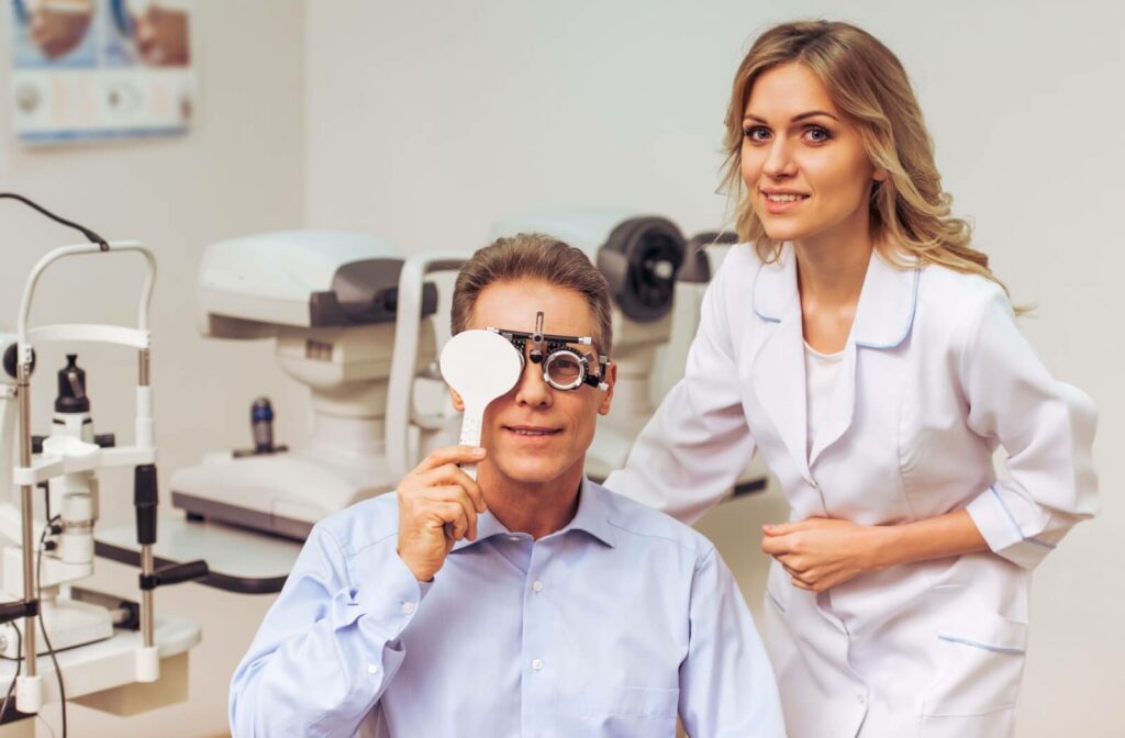 An optometrist guides their patient covering their eye through a visual acuity test to test their vision in an office.