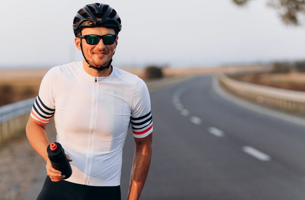 Road cyclist smiling while wearing protective sports sunglasses.