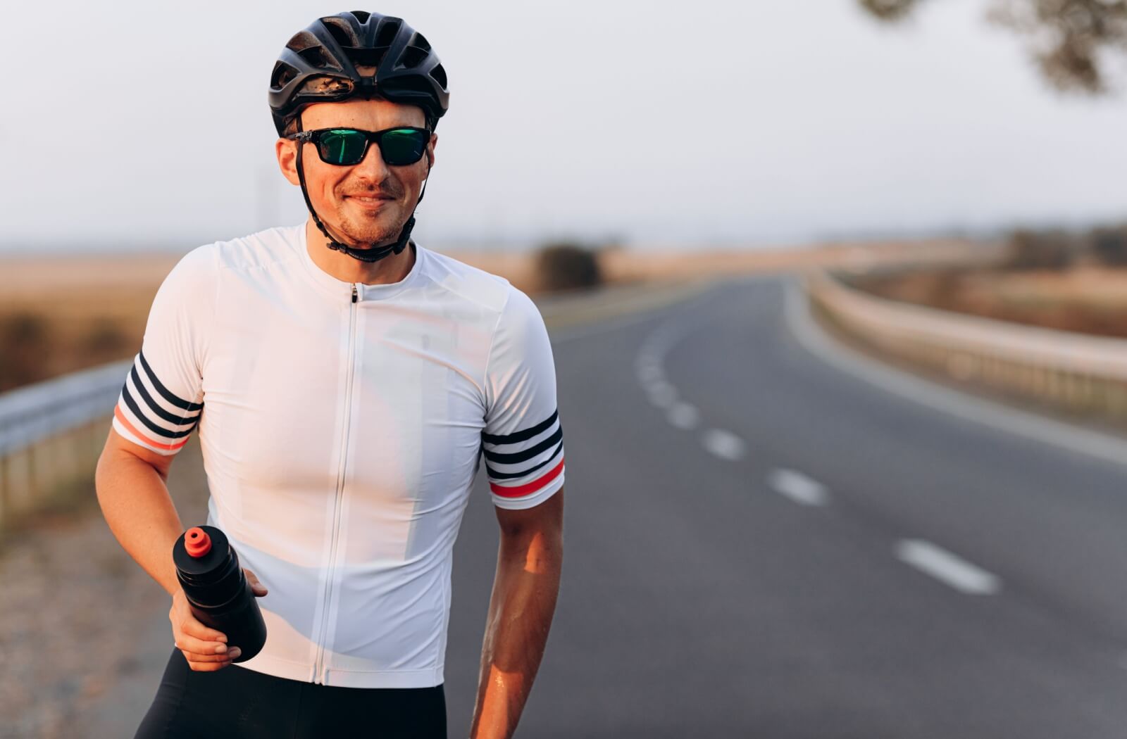 Road cyclist smiling while wearing protective sports sunglasses.